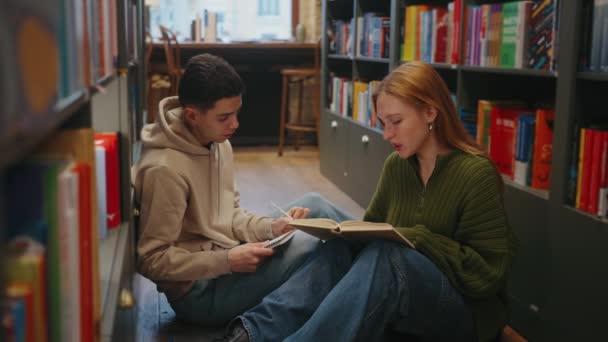 Öğrenci Rahat Kütüphane Zemininde Oturmuş Renkli Kitaplarla Dolu Arkaplanlarla Ortak — Stok video