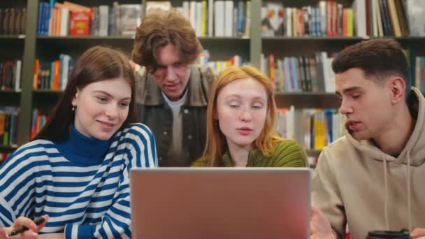 Four Students Collaborate Project Discussing Laptop Library Bookshelves Background Education — Stock Video