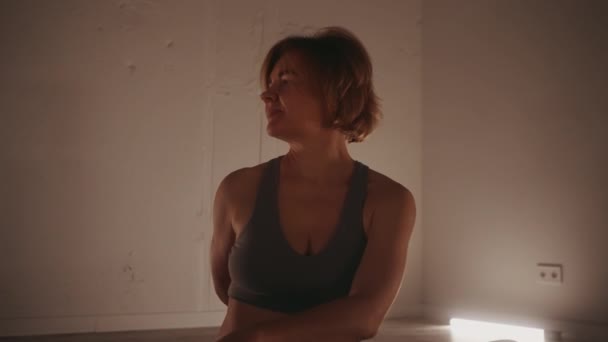 Mujer Practicando Yoga Sentado Giro Habitación Débilmente Iluminada Reflejando Tranquilidad — Vídeos de Stock