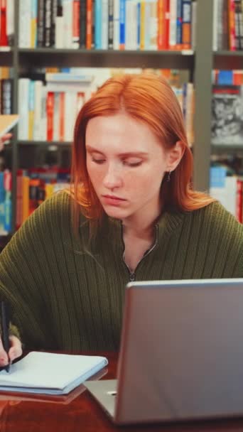 스크린 그녀의 노트북에서 일하고 학생들이 배경에서 화려한 도서관에서 테이블에 메모를 — 비디오
