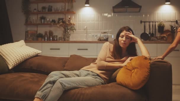 疲惫的母亲躺在沙发上 手挽着额头 当她的孩子们在客厅里嬉闹玩耍时 活泼的家庭生活 — 图库视频影像