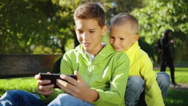 Dos Niños Con Sudaderas Verdes Amarillas Brillantes Enfocadas Teléfono Inteligente — Vídeo de stock