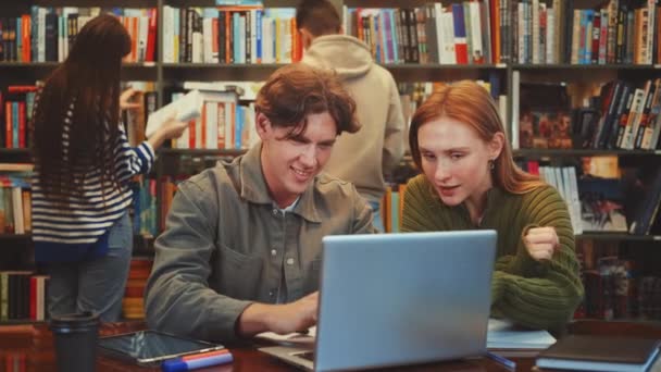 Два Целеустремленных Студента Участвуют Совместном Исследовании Используя Ноутбук Библиотечным Столом — стоковое видео