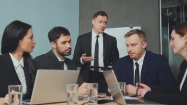 Bir grup iş adamı toplantıda, elinde tablet olan bir adam ve diğerleri tartışıyorlar. İş dünyası ekibi, başarılı sunumun ardından meslektaşlarını alkışladı