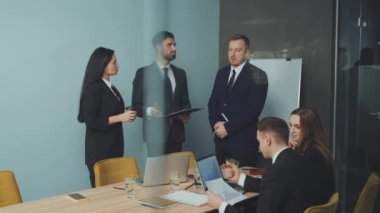 Molada iş arkadaşları takım elbise giyer, tartışmalarına gayri resmi olarak devam eder, bağlılığı ve takım çalışmasını yansıtır.