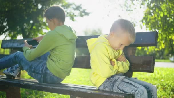 Νεαρό Αγόρι Φωτεινό Κίτρινο Hoodie Κάθεται Στο Παγκάκι Πάρκο Κατσούφιασμα — Αρχείο Βίντεο