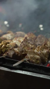 Kömür ızgarasında kızartılmış domuz eti parçalı şişler, onları döndüren eldivenler giyen aşçılar. Sokak fuarında el yapımı buharlı barbekü. Yiyecek kavramı