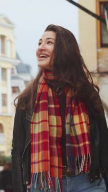 Dikey Ekran: Sonbahar şehrinde kareli eşarplı deri ceket giyen genç bir kadın kameraya bakıyor. Dışarıdaki mutlu kişiyi izliyoruz. Mutluluk kavramı