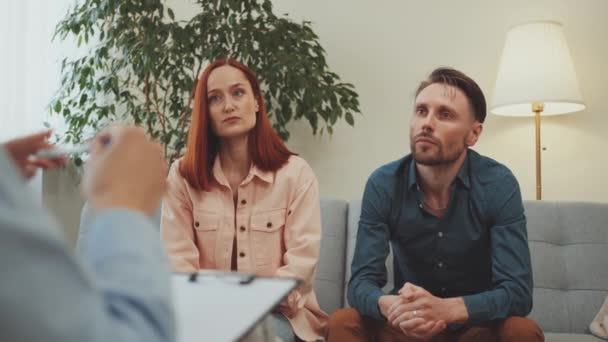 注意的心理学家在谈话中倾听男人的相关手势 而女人则以忧郁的表情坐在他旁边 两人都在进行心理治疗 — 图库视频影像