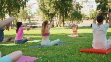 Yoga meraklıları şehir parkındaki paspaslar üzerinde esneme egzersizleri, fiziksel aktivite ve açık hava ortamının kombinasyonu yapıyorlar. Sağlık ve Sıhhat kavramı
