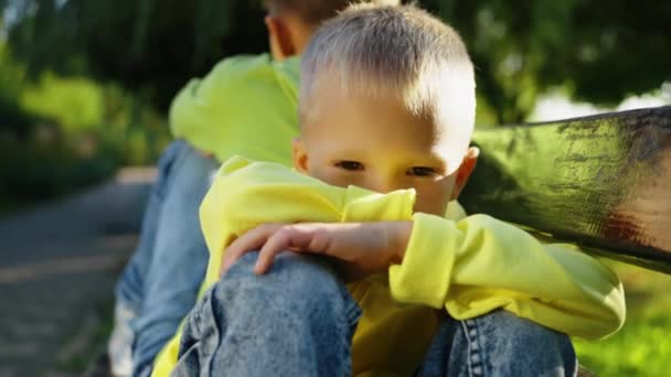 Bracia Siedzą Tyłu Ławce Parku Sporze Młody Chłopiec Żółtej Bluzie — Wideo stockowe