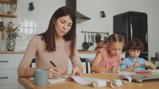 Matka Počítá Rodinný Rozpočet Kuchyňského Stolu Zatímco Její Děti Soustředí — Stock video