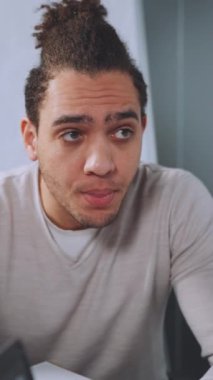 Dikey ekran: Düşünceli ve endişeli takım lideri ekip üyelerinin şirket toplantısı sırasında ateşli tartışmalara girişini izliyor