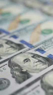 Dikey ekran: 100 dolarlık banknotların Dolly çekimi düzgün bir şekilde Benjamin Franklin 'in yüzüne odaklanıyor. Kamera Amerikan para biriminin yanında hareket ediyor. Maliye ve para ödemesi kavramı