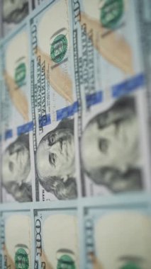 Dikey ekran: Para çevirme. Sıraya dizilmiş yüz Amerikan doları Benjamin Franklin 'in portresine odaklanıyor. Banknotlar başarıyı simgeliyor. Maliye ve para ödemesi kavramı