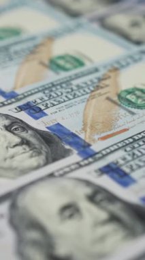 Dikey ekran: 100 dolarlık banknotlar aşağı doğru döner bir tablo üzerinde çırpınarak para ve zenginlik dansı oluşturur
