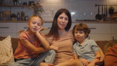 Anne iki çocuğuyla birlikte kanepede oturup televizyon izliyor. Aile bağları ve evde geçirilen kaliteli zaman kavramı