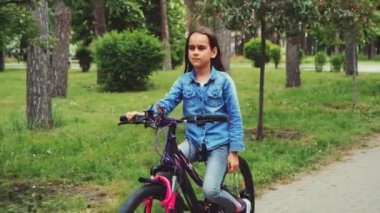 Bisikletle parkta gezen, doğa ve doğa aktivitelerinin tadını çıkaran bir kız. Sağlıklı yaşam tarzı ve çocukluk macerası kavramı