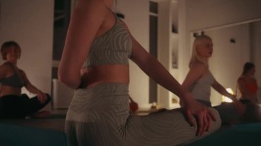 Stüdyoda yoga yapan kadınlar pozlarına odaklanmış. Yumuşak ışıklandırma huzurlu ortamı geliştirir. Farkındalık, fiziksel uygunluk ve zihinsel rahatlama kavramı