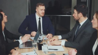 İş adamları tokalaşma anlaşmasıyla toplantıyı tamamladı. Takım elbiseli iki adam konferans masasında el sıkışıyor. Ekip üyeleri izleyin. Başarılı müzakere ve takım çalışması kavramı