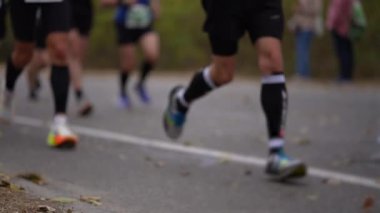 Yolda maraton koşan koşucular. Alt bedenlere ve kaldırımdaki koşu ayakkabılarına odaklan. Dayanıklılık, zindelik ve atletik rekabet kavramı.