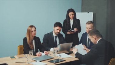 Ofis toplantısı sırasında iş birliği yapıp planları tartışıyor ve belgeleri gözden geçiriyorlar. Lider talimat veriyor. Takım çalışması, işbirliği ve proje yönetimi kavramı