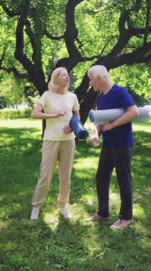 Sunny Park 'taki yoga seansından sonra yoga minderleri tutan yaşlı bir çift su içip sohbet ediyor. Aktif ve sağlıklı yaşlı yaşam tarzı ve susuzluk kavramı