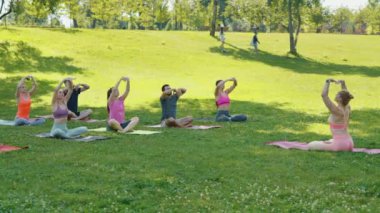 Katılımcıların minderlere oturduğu grup yoga seansı, eğitmenin rehberliği altında ileriye doğru uzanıyor. Toplumsal refah ve farkındalık kavramı