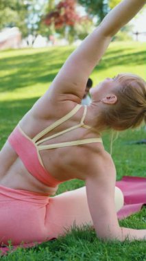Dikey Ekran: Yoga eğitmeni gruba parkta nasıl oturulacağını gösteriyor. Katılımcılar da bunu izleyerek esneklik ve dengeyi artırıyorlar. Sağlıklı yaşam tarzı kavramı