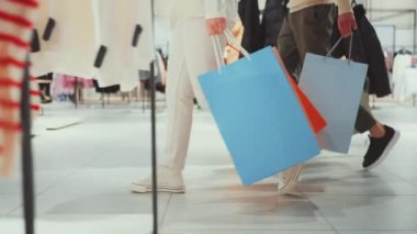 Markette alışveriş torbalarıyla yürüyen bir çift. Çantalara ve bacaklarına odaklan. Alışveriş, perakende terapi ve birlikte zaman geçirme kavramı..