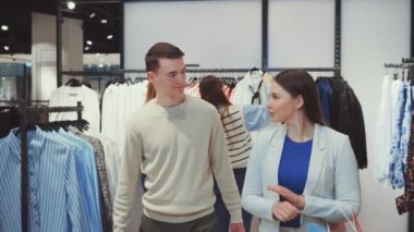 Giyim mağazasında alışveriş yapan, alışveriş torbaları taşıyan ve alışverişleri tartışan çiftler. Çift ilişkileri, perakende terapisi ve moda alışverişi kavramı