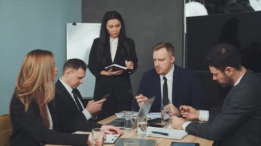 Patron toplantıyı yönetiyor ve talimatları veriyor. Çalışanlar dikkatle dinler ve not alır. Profesyonel iş ortamında takım çalışması ve işbirliği. Liderlik ve yönetim kavramı