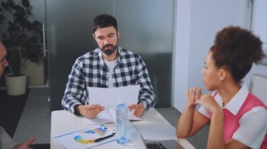 Modern ofisteki masa etrafında iş birliği yapan çeşitli çalışma gruplarını yakınlaştır. Katılımcılar masadaki tabletler, dizüstü bilgisayarlar ve defterlerle tartışmaya giriyorlar. Takım çalışması ve üretkenlik kavramı