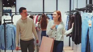 Giysi mağazasında alışveriş yapmaktan hoşlanan çift çeşitli kıyafetleri karıştırıyor ve alışverişleri tartışıyor. İlişki bağı, moda ve perakende deneyimi kavramı