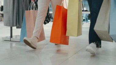 Alışveriş merkezinde renkli alışveriş torbalarıyla gezen yakın çekim kadınları. Tüketim anlayışı, perakende terapi ve alışveriş keyfi.