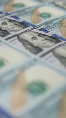 Dikey ekran: Dolly 'nin nakit parası. Sıraya dizilmiş yüz Amerikan doları Benjamin Franklin 'in portresine odaklanıyor. Banknotlar başarıyı simgeler. Maliye ve para ödemesi kavramı