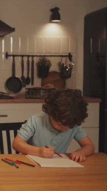 Dikey ekran: Çocuk renkli kalemlerle masada çizim yapmaya odaklanıyor. Yaratıcılık ve evde öğrenme kavramı. Çocuğa odaklan sanatsal gelişim ve evde eğitim