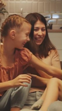 Dikey ekran: Bekar anne çocuklarıyla kaliteli zaman geçirir, birlikte güler ve kanepede oynar. Aile bağı ve bekar ebeveynlik kavramı. Aile hayatında sevgi, bağ ve neşe