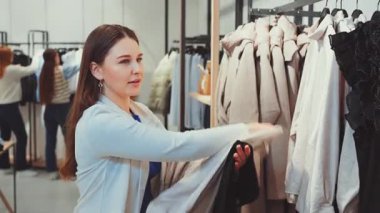 Kadın mağazada birkaç parça kıyafet tutuyor, daha fazla seçeneği incelerken gülümsüyor. Alışveriş bağımlılığı, moda tutkusu, perakende terapisi ve yeni kıyafetler seçmenin keyfi.