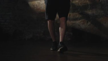 Yeşil kapüşonlu atletik bir adam, duvarları açık, loş ışıklı bir spor salonunda sıkı bir boks antrenmanı sırasında ip atlarken görüldü.