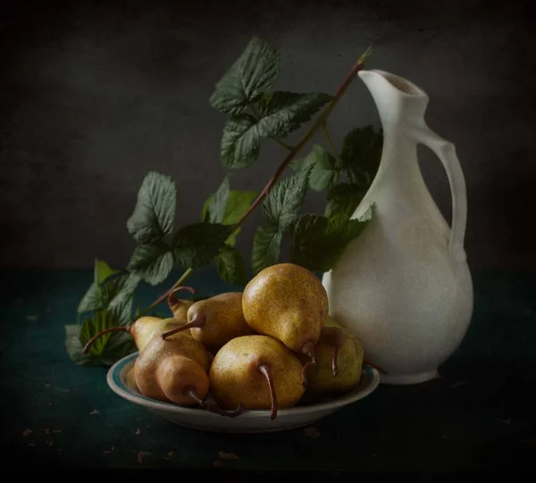 Tahta arka plandaki bir kasede taze armutlar.