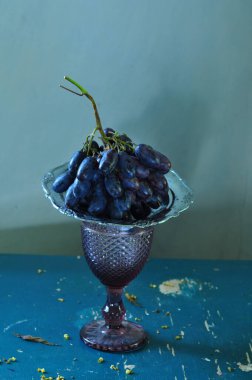 Koyu arkaplanda cam bir kasede taze üzümler..