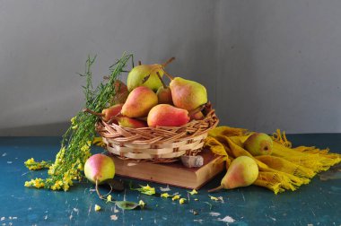 Tahta bir arka planda sepetteki olgun armutlar.