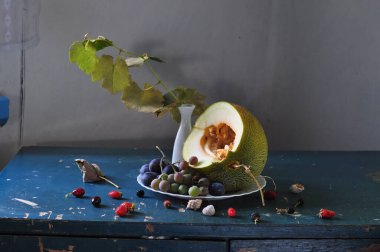 Olgun kavun, üzüm ve bir buket yaz çiçeği.