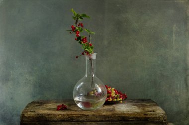 Durgun bir hayat, eski bir hayat. Yaban gülü ve kırmızı üzümlü vazo ahşap masada. 