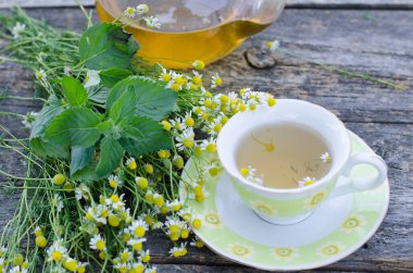 çay, papatya çayı, yabani çiçekler, otlar ve çay fincanı ahşap arka planda, bitkisel tıp konsepti 