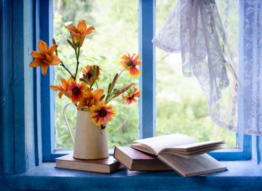 Ahşap masanın üzerinde çiçekler olan klasik bir kitap.