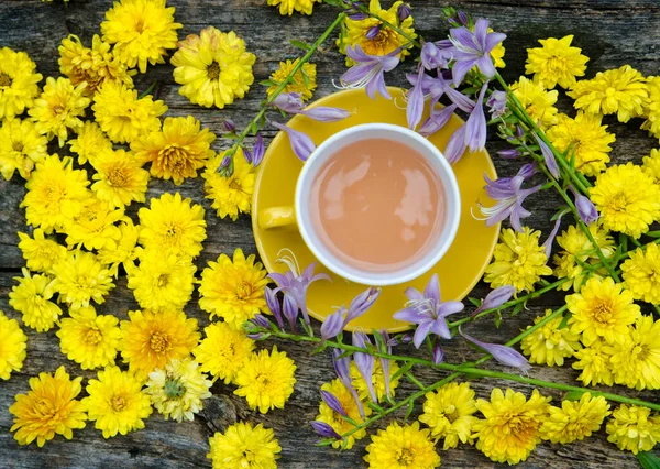 Bir fincan çay, kahve, limon, yeşil bir masada sarı çiçekler..