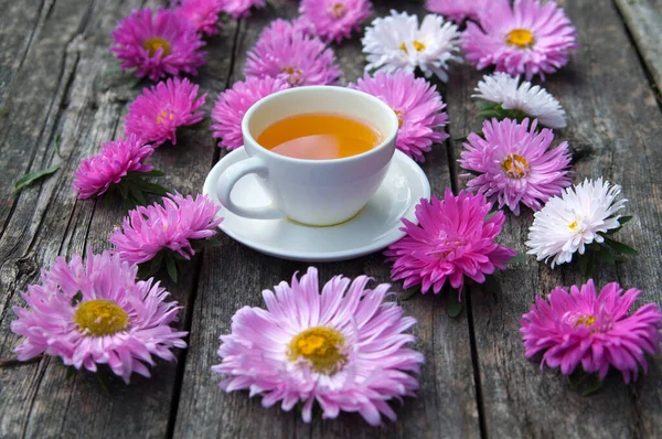 Tahta bir tahtanın üzerinde pembe kasımpatı çiçekleri olan çay fincanı. seçici odak. 