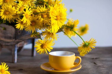 Tahta masada sarı kasımpatı çiçekli bir fincan kahve, mesaj için yer. 